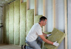 A man carefully installs insulation in a room
